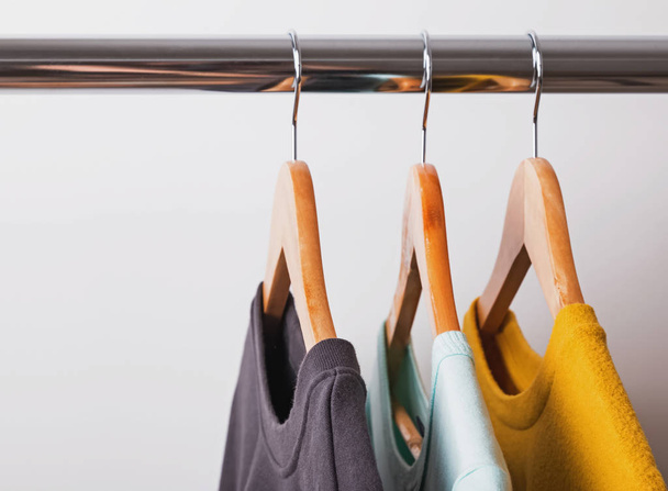 Cozy sweaters of different colors on wooden hangers - 写真・画像