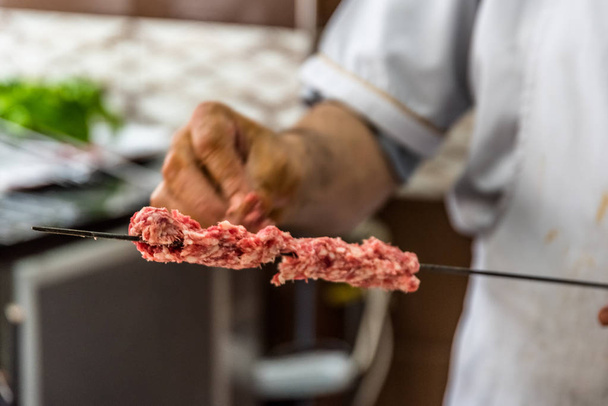 Uomo mano preparare tradizionale delizioso spiedo spiedino shish kebab turco fatto di fegato di agnello
. - Foto, immagini