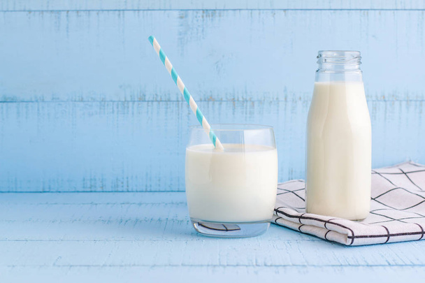A bottle and a glass of milk on blue wooden background. - Fotografie, Obrázek