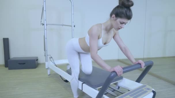 Pilates. Γυναίκα με λευκά ρούχα άσκηση τεντώνοντας άσκηση σε μεταρρυθμιστής στο γυμναστήριο. όλες τις σειρές με αριθμό 01234567890001. - Πλάνα, βίντεο
