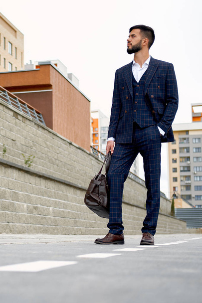 Attractive businessman walking down the street holding travel bag - Fotó, kép