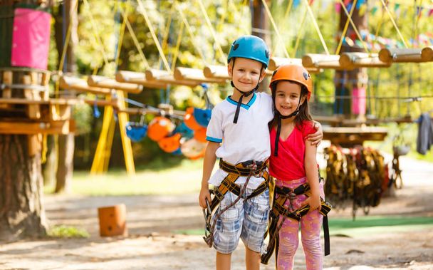 Μικρό παιδί αγόρι και κορίτσι, αναρρίχηση σχοινιά του εξοπλισμού σε μια παιδική χαρά για το καλοκαίρι - Φωτογραφία, εικόνα