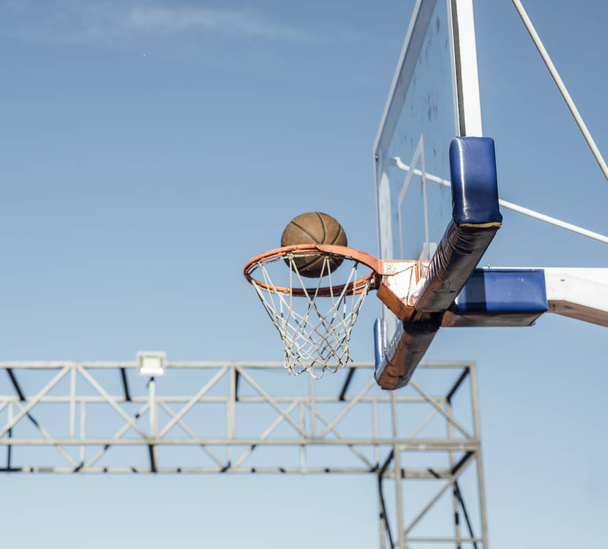 Ball on basketball ring on outdoor court. - Foto, afbeelding