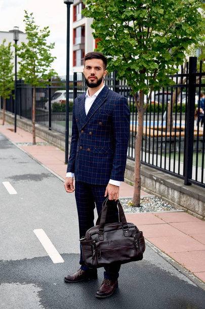 Attractive businessman walking down the street holding travel bag - Fotografie, Obrázek