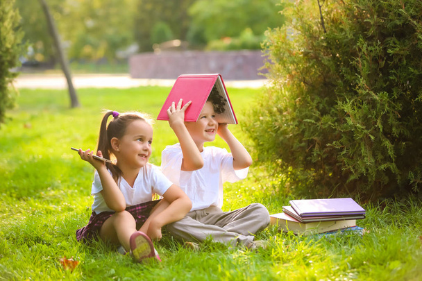 Jungen und Mädchen amüsieren sich im grünen Park mit Büchern - Foto, Bild