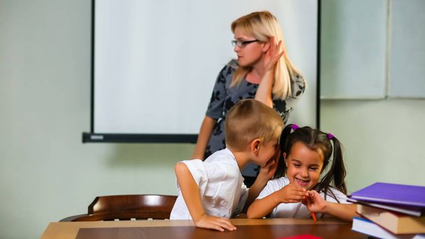 bambino e ragazza che studiano seduti alla scrivania ascoltando la spiegazione dell'insegnante
  - Foto, immagini