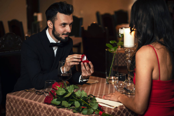 Man surprising woman with engagement ring at the restaurant during romantic dinner - Photo, Image