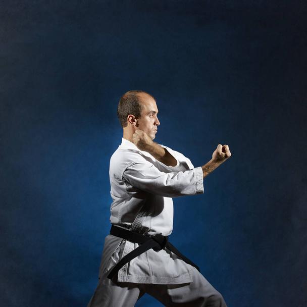 Een mannelijke atleet voert formele karate oefeningen - Foto, afbeelding