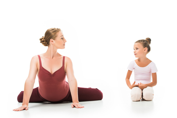 lächelnde erwachsene Trainerin, die der kleinen Ballerina auf weißem Hintergrund Übungen zeigt  - Foto, Bild