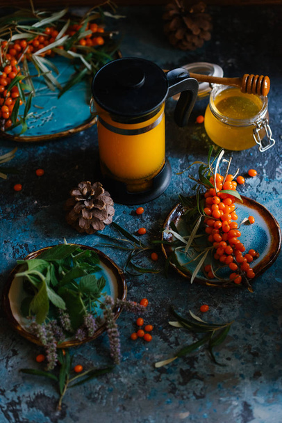 新鮮な sandthorn ジュースのフレンチ プレスと新鮮な sandthorn ベリーと青の具体的背景に蜂蜜 - 写真・画像