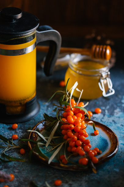 Fresh sandthorn juice in french press with fresh sandthorn berries and honey on blue concrete background - Фото, зображення