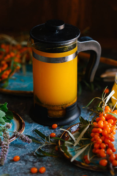 Fresh sandthorn juice in french press with fresh sandthorn berries and honey on blue concrete background - Fotografie, Obrázek