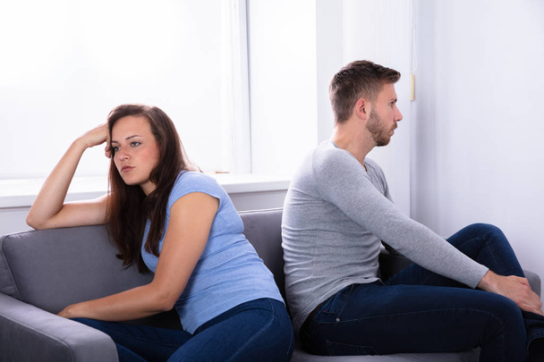 Upset Young Couple Sitting On Sofa At Home - Photo, Image