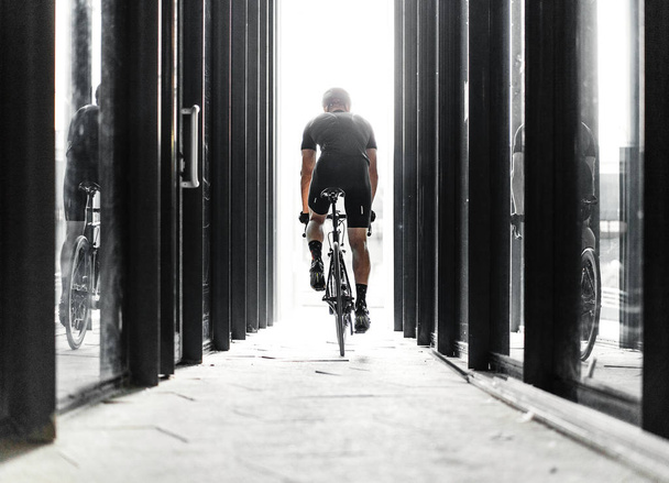 Sport bike man riding inside urban modern glass tunnel with light. Cyclist on professional bicycle training day.Concept of active lifestyle and outdoor hobby. - Φωτογραφία, εικόνα