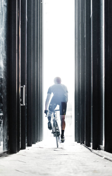 Sport bike man riding inside urban modern glass tunnel with light. Cyclist on professional bicycle training day.Concept of active lifestyle and outdoor hobby. - Photo, image