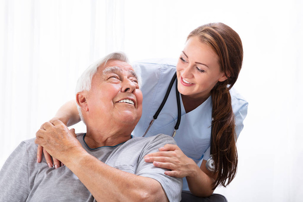 Portrait Of A Happy Female Nurse Looking At Senior Man - Foto, Imagen