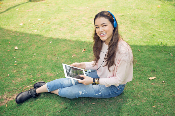 Jolie étudiante vietnamienne assise sur le campus avec tablette
 - Photo, image