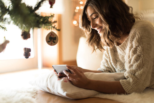 Femme utilisant un smartphone à la maison - Hiver et Noël
 - Photo, image