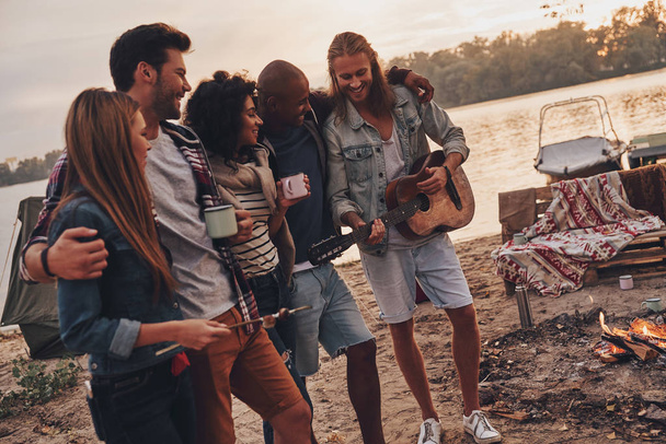 best friends enjoying beach party near campfire with drinks and guitar  - Foto, Imagen