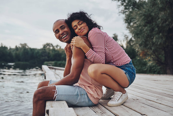 romantyczna para w miłości Ogarnięcie i siedzi na molo nad jeziorem  - Zdjęcie, obraz