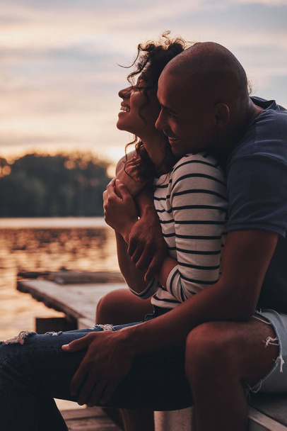 Verliebtes Paar umarmt und sitzt auf Seebrücke  - Foto, Bild