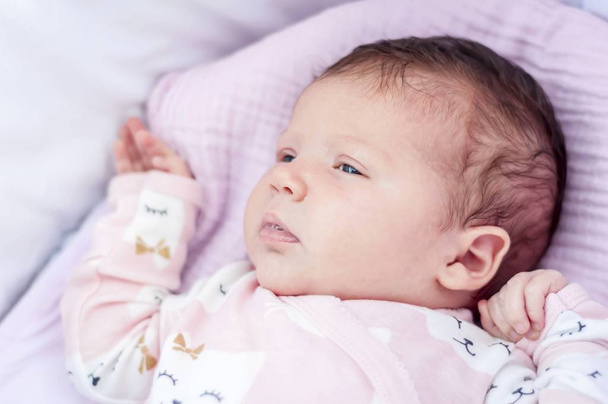 Lindo bebé recién nacido adorable con los ojos abiertos acostado en la cuna o carro de bebé
. - Foto, imagen