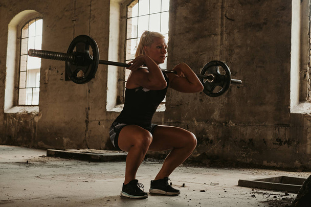 Atleta feminina forte na posição de agachamento frontal mais baixa
 - Foto, Imagem