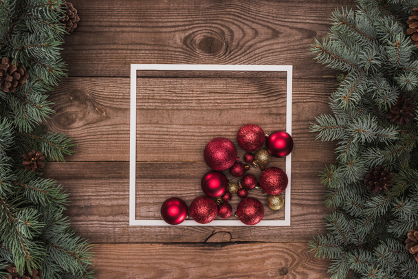 白フレーム、光沢のある赤と金色のボールおよびマツ円錐形、クリスマスの背景で針葉樹の枝の平面図  - 写真・画像