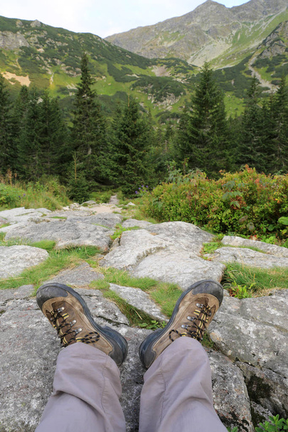 Hikers legs in boots on stone in mountains - Zdjęcie, obraz