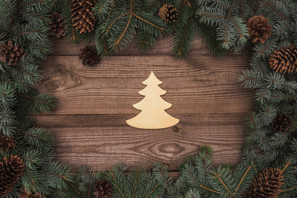 top view of beautiful christmas tree symbol and coniferous branches with pine cones on wooden background - Photo, Image
