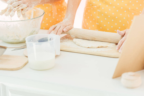 cropped shot of mother and daughter kneading dough together isolated on pink - Фото, зображення