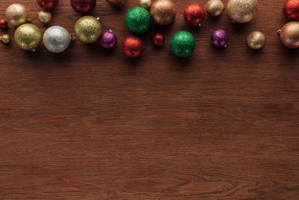 top view of beautiful shiny colorful baubles on wooden surface, christmas background - Foto, Imagem