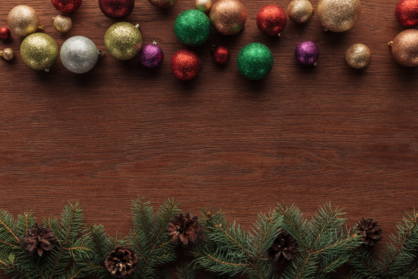 vue de dessus des boules colorées brillantes et des brindilles de conifères avec des cônes de pin sur fond en bois
  - Photo, image
