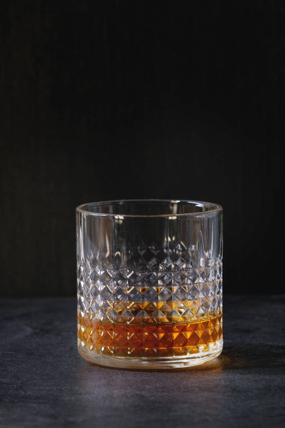Glass of scotch whiskey standing on black marble table. Alcohol drink. - Foto, afbeelding