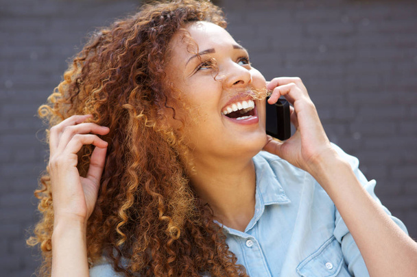 Закрыть портрет счастливой молодой женщины, смеющейся и разговаривающей по мобильному телефону
 - Фото, изображение