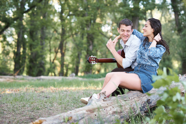 bir günlük ormanın içinde oturan ve iskambil gitar, yaz doğa, romantik duygular genç çift - Fotoğraf, Görsel