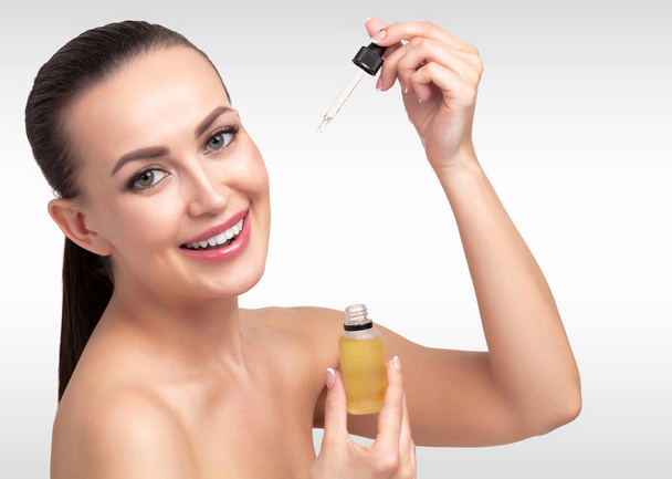 Closeup shot of cosmetic oil applying on young woman's face with pipette. Beauty therapy concept. - Photo, Image