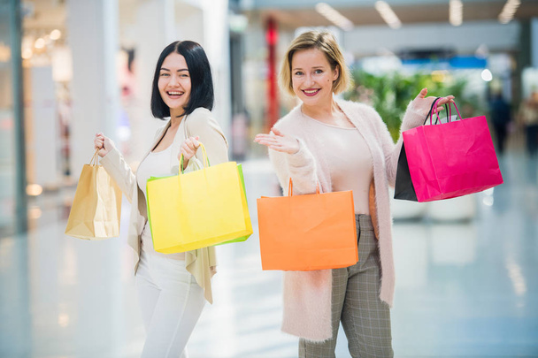 Две счастливые подруги девушки с сумками для покупок прогуливаются по магазинам
 - Фото, изображение