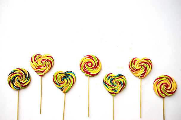 sucette multicolore tourbillonner de grands bonbons sur bâton en bois hipster arc-en-ciel coloré isolé sur fond blanc, plat laïc
 - Photo, image