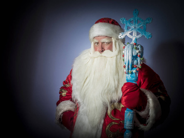 A traditional Christmas Santa Clause with staff on blue background - Photo, Image