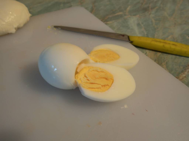 un huevo recién hervido cortado en mitades en una pizarra blanca
 - Foto, Imagen