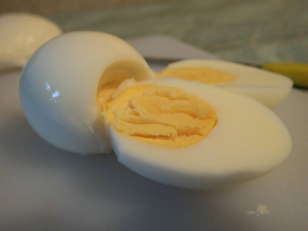 čerstvé vařené vejce nakrájíme na poloviny na bílou tabuli - Fotografie, Obrázek