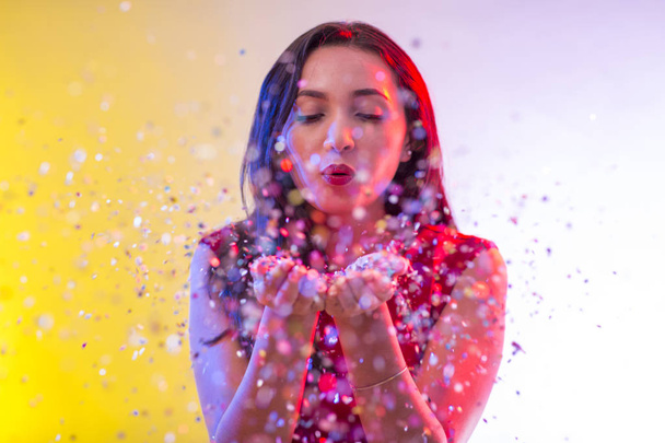 Belle fille sur fond de fête soufflant confettis
 - Photo, image