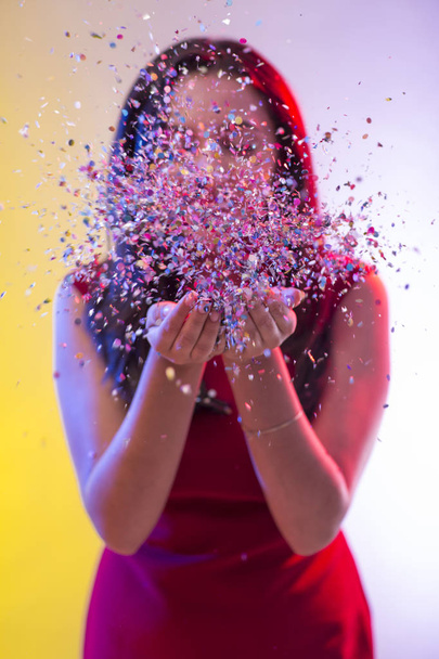 Beautiful girl on party background blowing confetti - Fotoğraf, Görsel