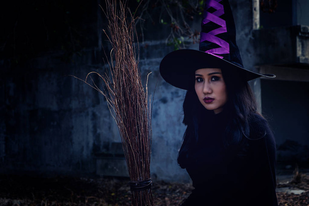 Mujer joven con disfraz de bruja de Halloween sostienen una flor de mago sobre el aterrador fondo oscuro
. - Foto, Imagen