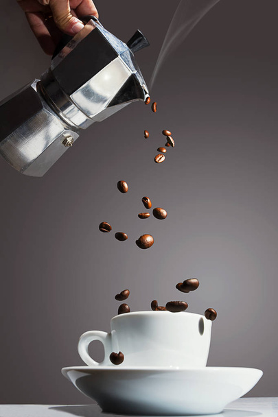Кофейник наливает жареные кофейные зерна в чашку
 - Фото, изображение