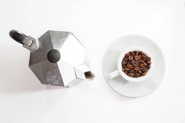 Cafetera y granos de café tostados en la taza desde arriba
 - Foto, imagen