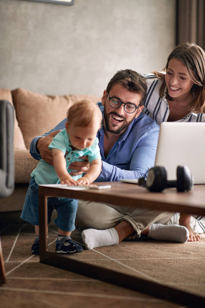 Young parents with baby working from home using laptop - Photo, image