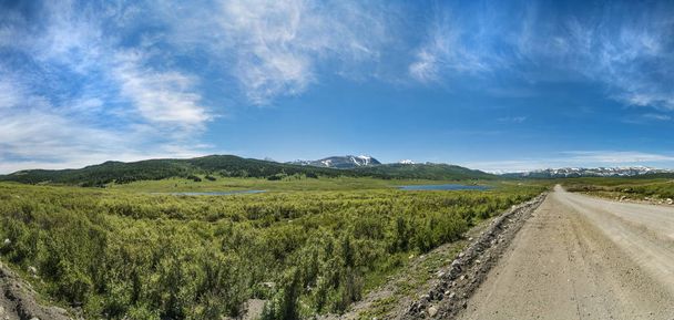 A beautiful and majestic view and a panorama of the natural and wild nature. Panorama and a scene of beautiful and majestic mountains and a country road in summer against a blue sky. Altai, Siberia, Russia. - Photo, Image