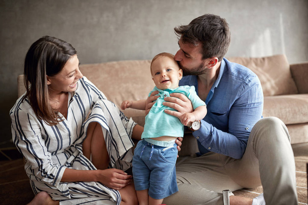 proud parents mother and father kissing little cute baby boy at home - Foto, imagen